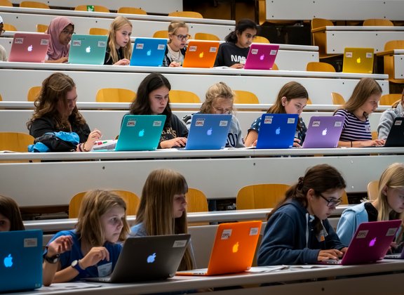 Des MacBooks colorés dans un cours universitaire