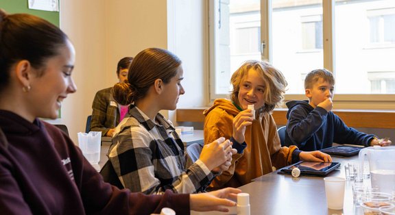 Des élèves expérimentent dans une salle de classe lors du TecDay et rient.