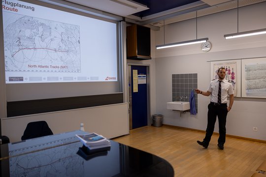 Il pilota presenta il piano di volo davanti a una mappa.